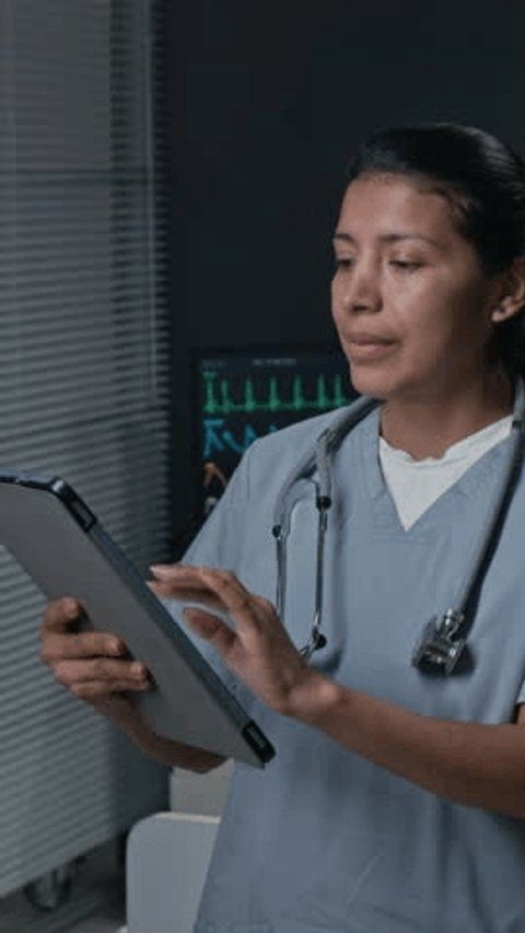 Ärztin bedient ein Tablet vor einem klinischen Monitor