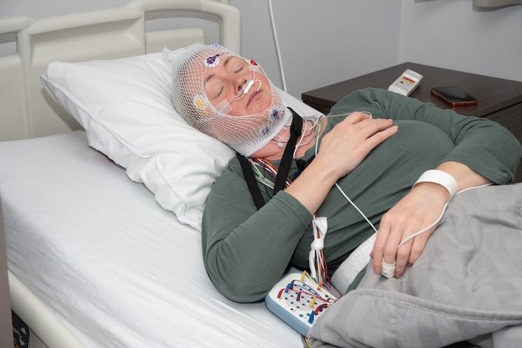 Schlafende Person mit Elektroden und Messgeräten in einem Klinikbett